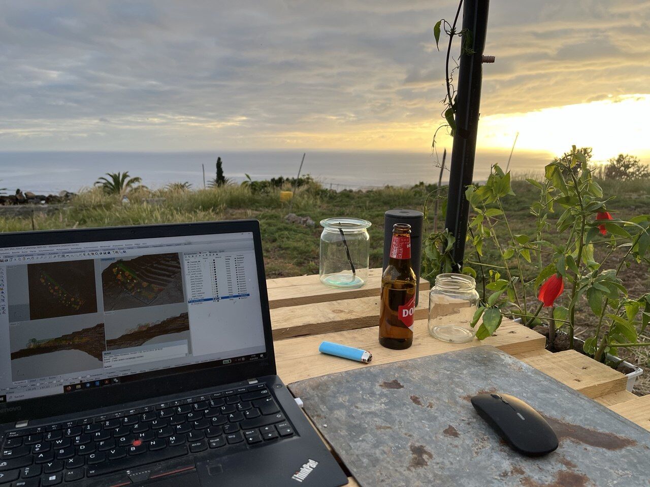 Laptop mit 3D-Geländemodell am improvisierten Tisch, Sonnenuntergang über dem Meer