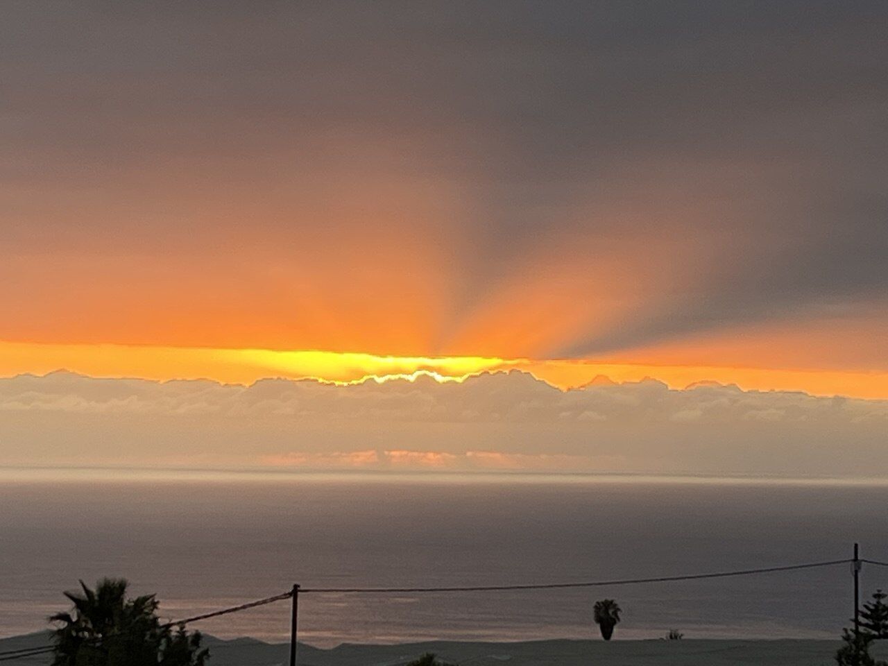 Sonnenstrahlen brechen durch eine Wolkenbank über dem Meer